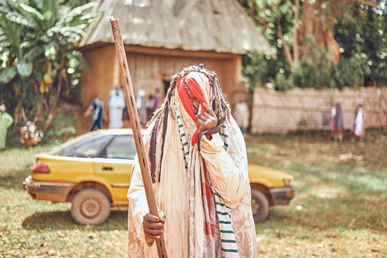 an older man in traditional clothing carries a stick in his hand