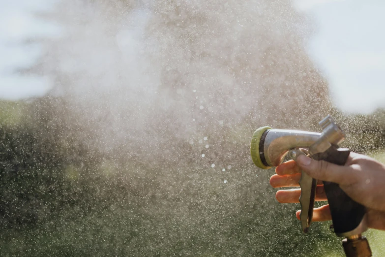 a person holds a blow gun and sprays water off their fingers