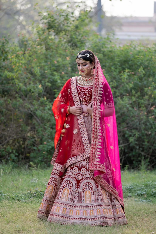 the bride in an indian wedding outfit walks along a field