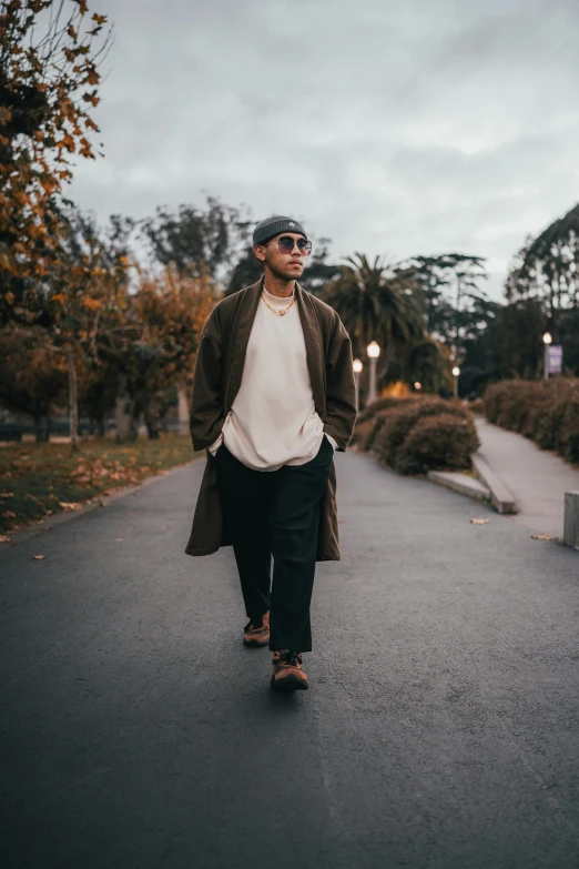 a man wearing a white shirt and brown jacket walks on an empty street