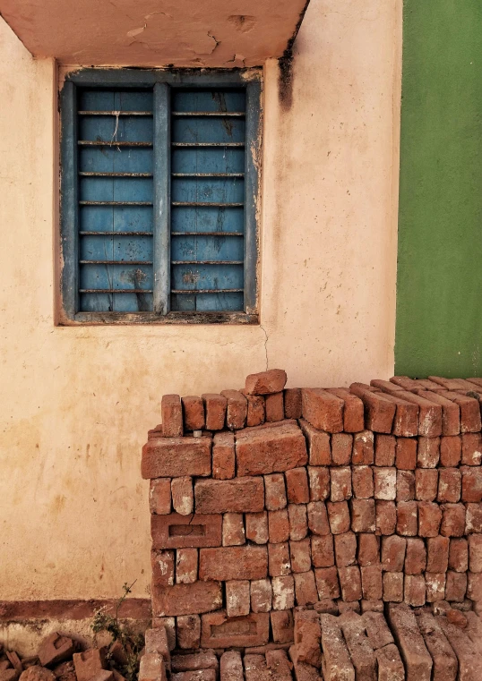 small brick piles sit in front of a window in a yellow wall