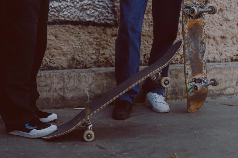 two people wearing blue jeans, one on a skateboard