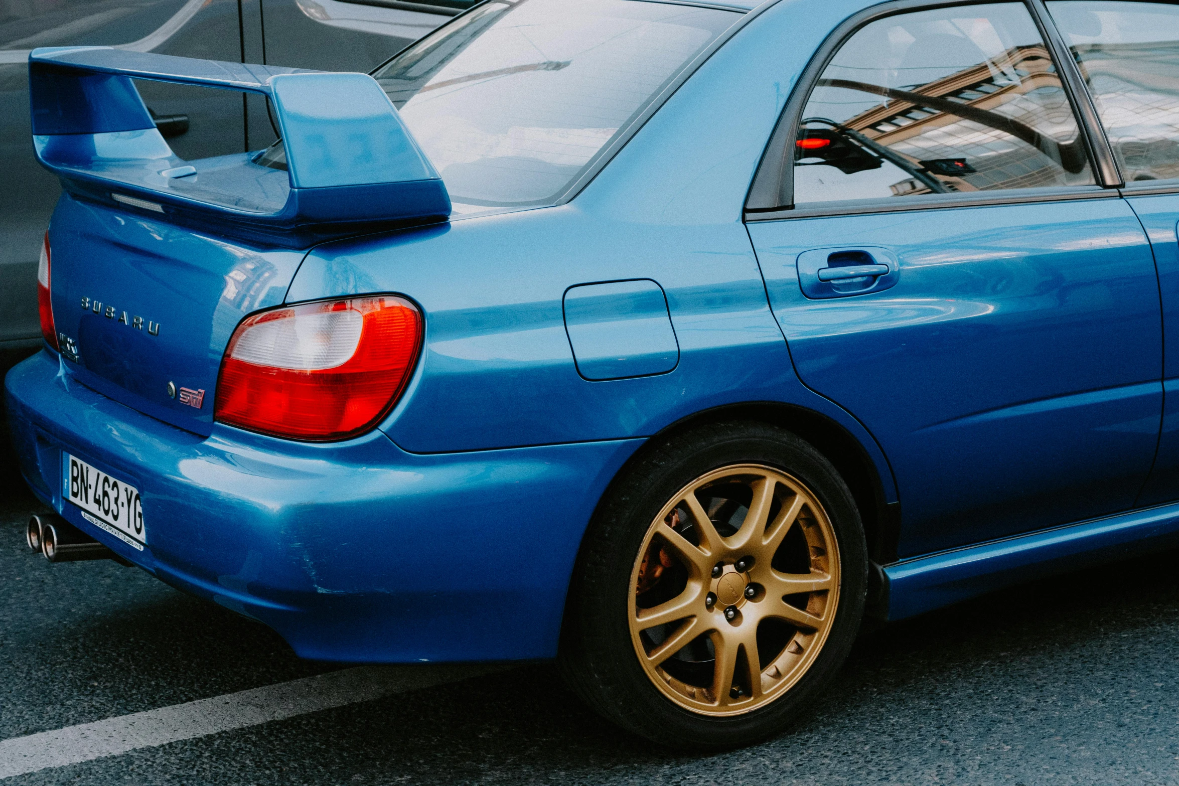 an orange rim sits in front of a blue sports car