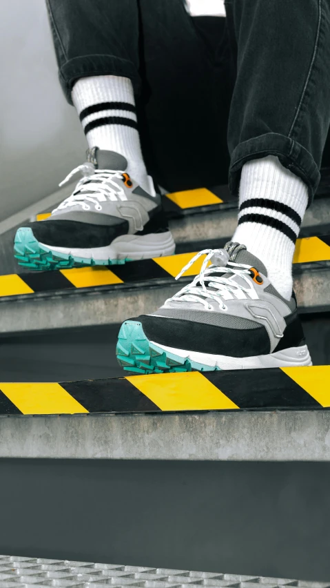 the legs of a man in sneakers and socks are on steps with yellow black and white stripes