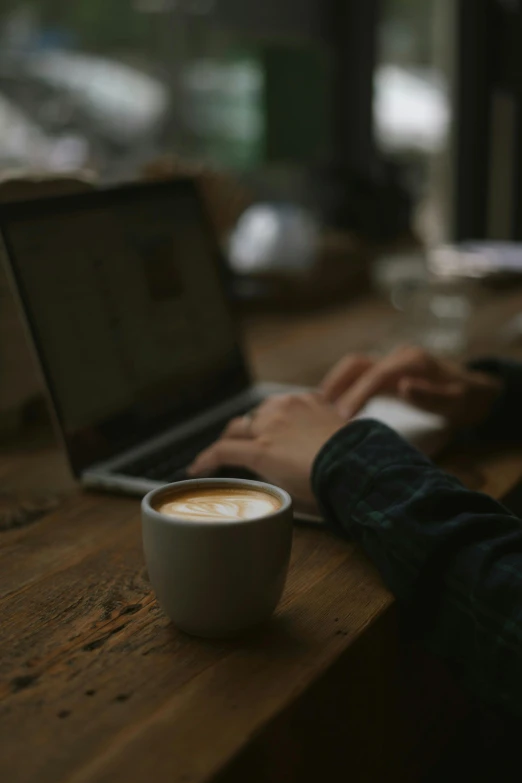 someone using a laptop at a restaurant with a cup of coffee