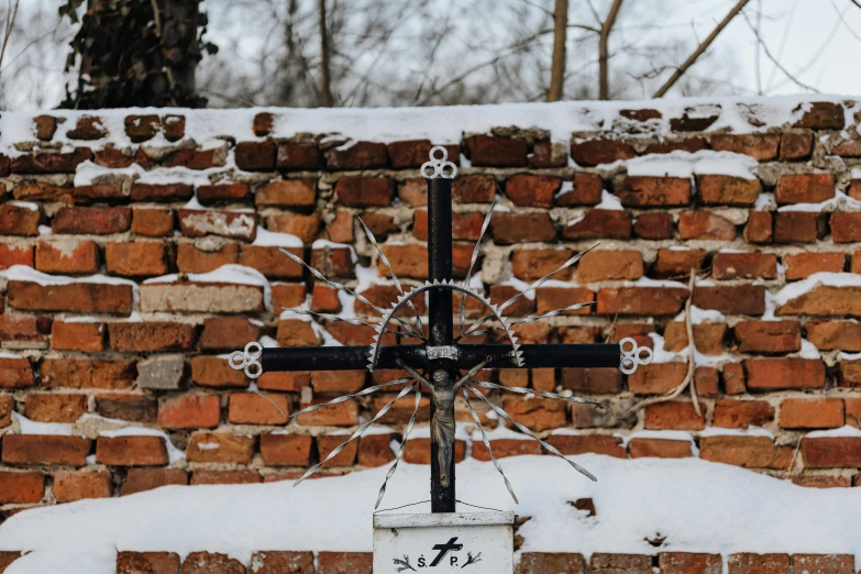 a very large cross in front of a brick wall