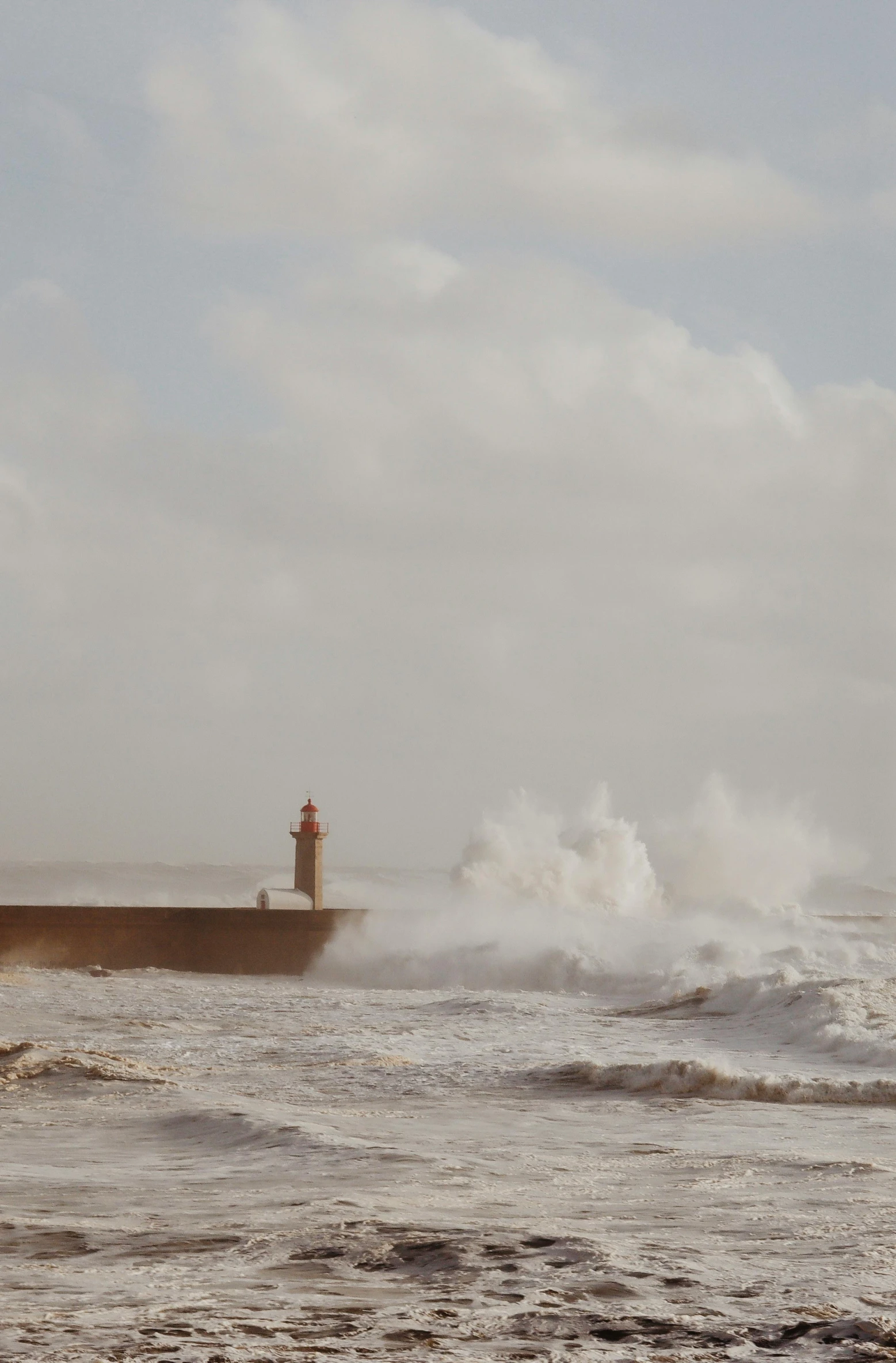 a small lighthouse with a huge wave in the background