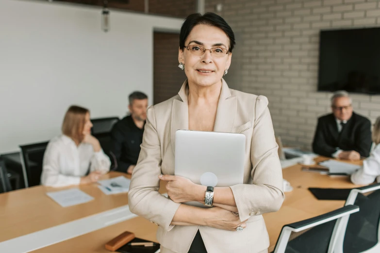 a woman in a meeting room standing with her arms crossed and smiling for the camera