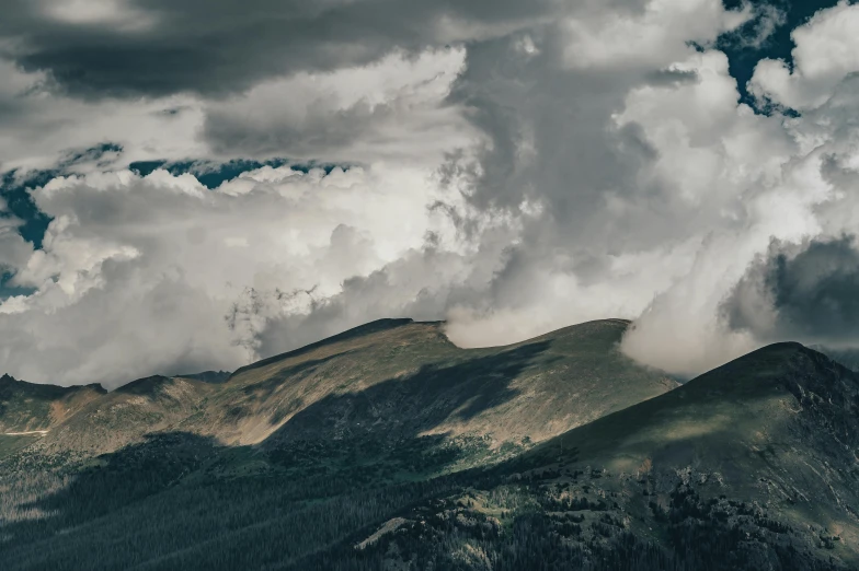 mountains under cloudy skies with trees below