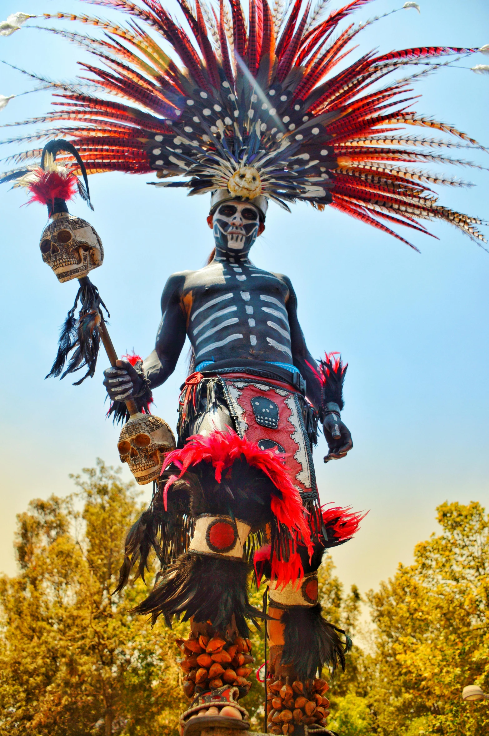 a statue in full native clothing is holding a staff