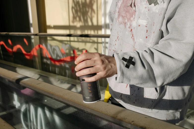 a man in a grey sweater is holding his spray paint