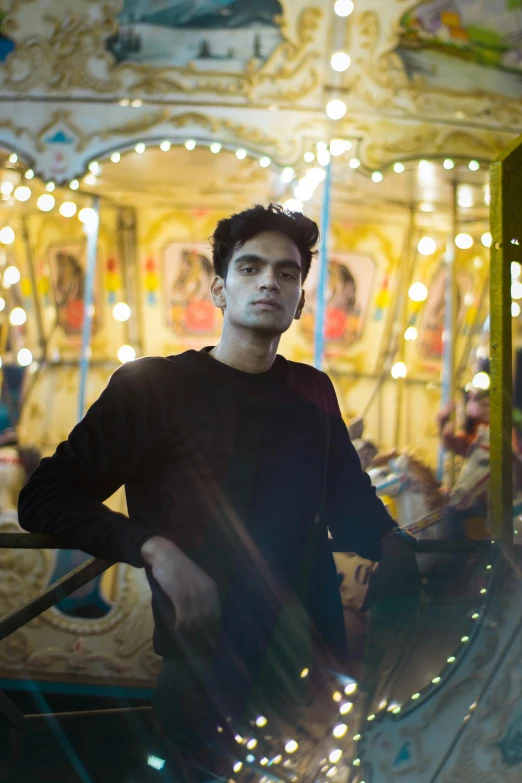 young man with a black shirt on standing in a merry go round