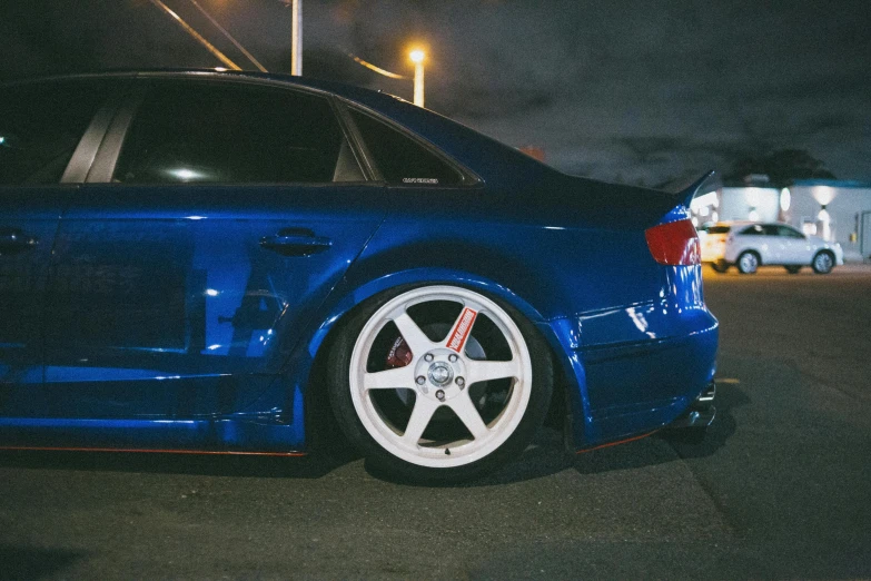 a blue car is parked in a parking lot at night