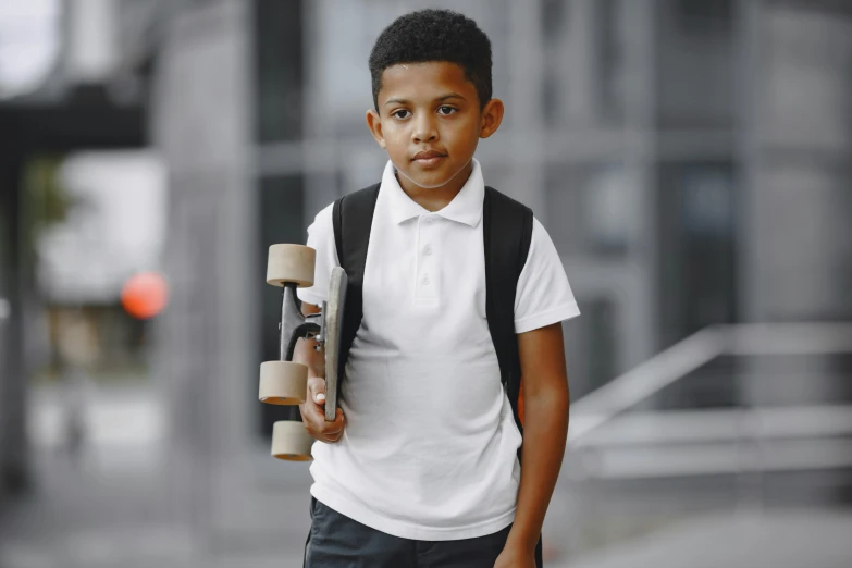 a boy carrying a skateboard and walking