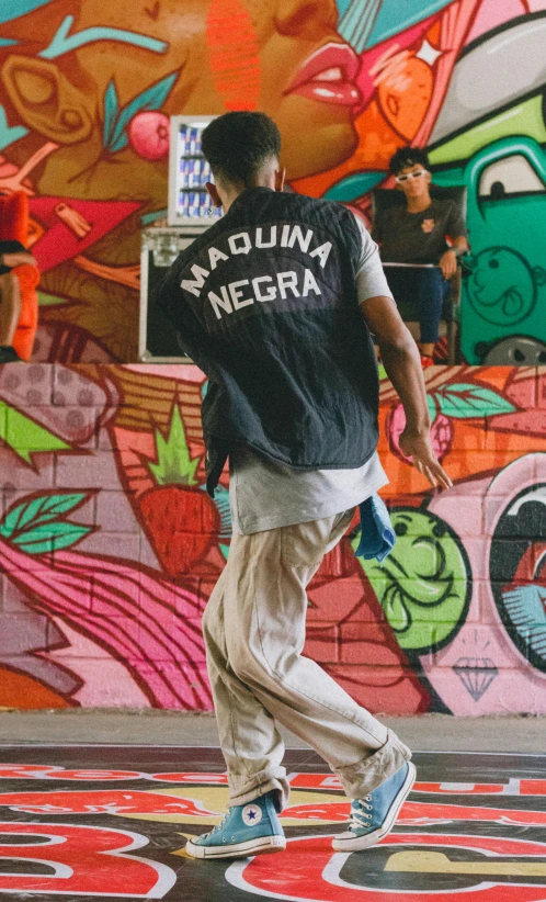 a man walking down a street in front of a wall with a large mural