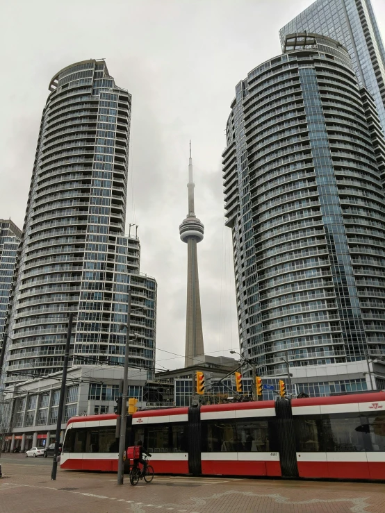 a train next to tall buildings in front of a tv tower