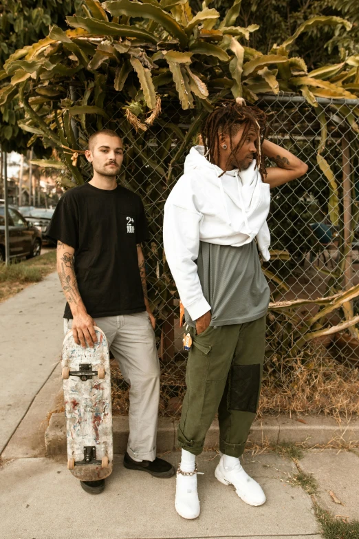 two young people hold skateboards and talk to the camera