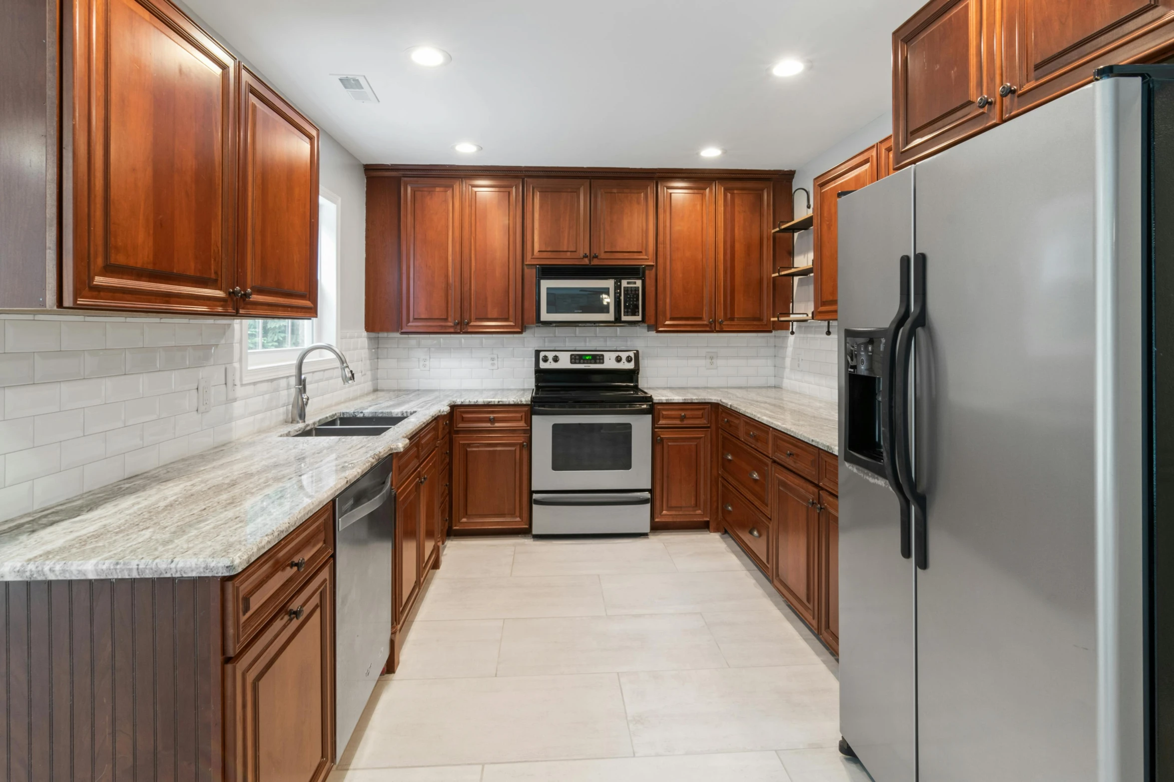 a white tiled floor and a shiny refrigerator in a small kitchen