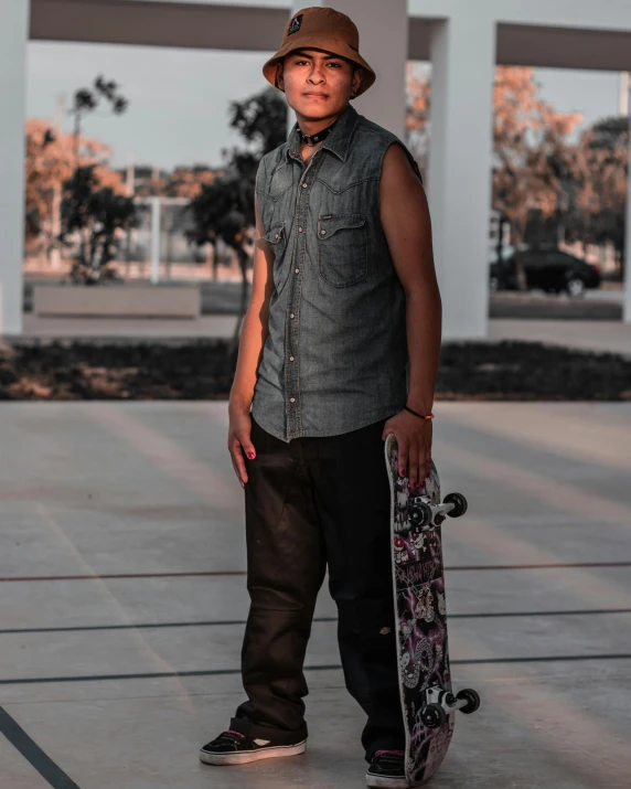 a young man in his 20s wearing a hat holding a skateboard