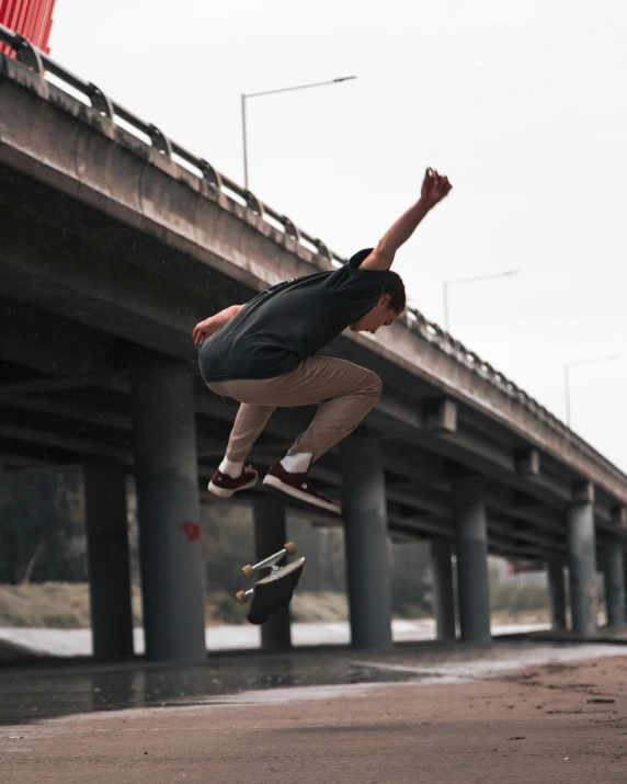 young male skateboarder in mid air going under overpass