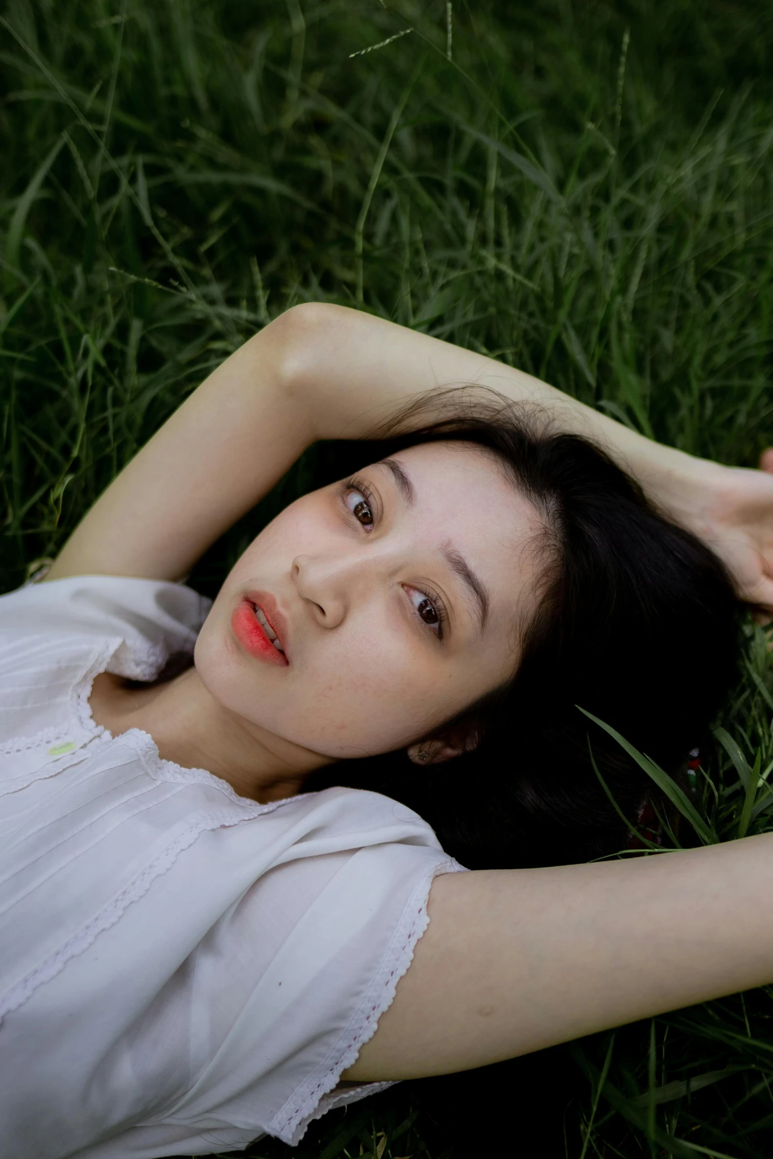 a woman lays down in grass while she's holding her arm out