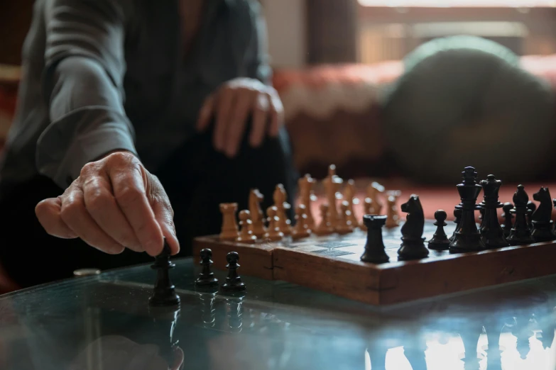 someone playing chess on a wooden board with chess pieces in hand