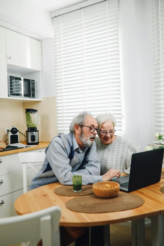 an elderly man sitting next to a woman with a laptop