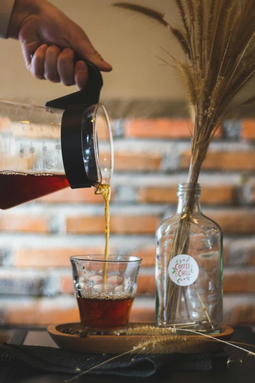 a person pouring a glass of wine in front of a bottle