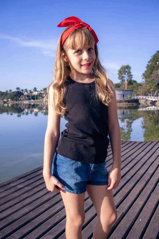 a  wearing a red bandana standing on a deck next to a body of water