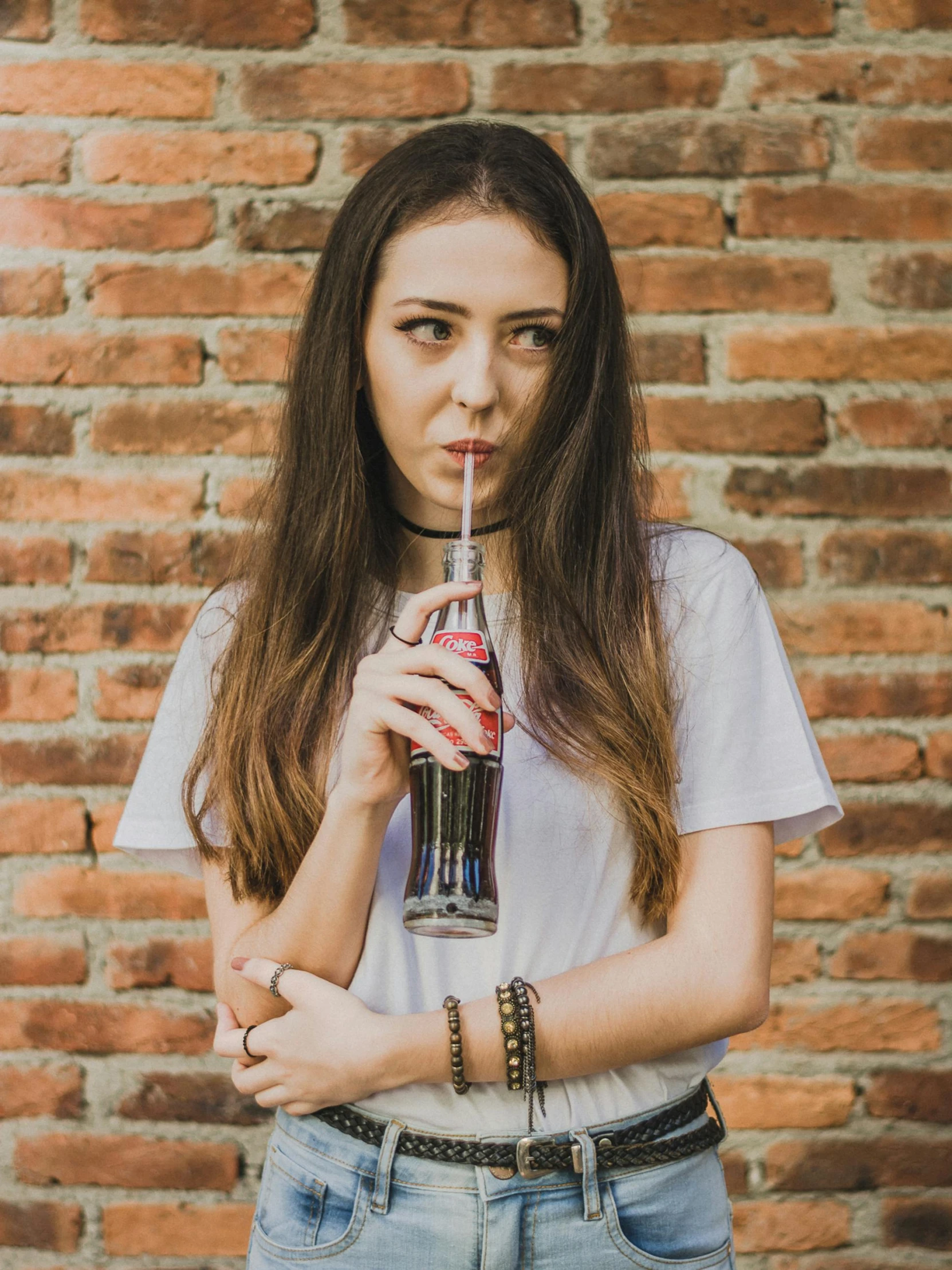 a woman with long brown hair drinking from a bottle