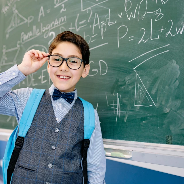 a  with glasses standing by the chalkboard