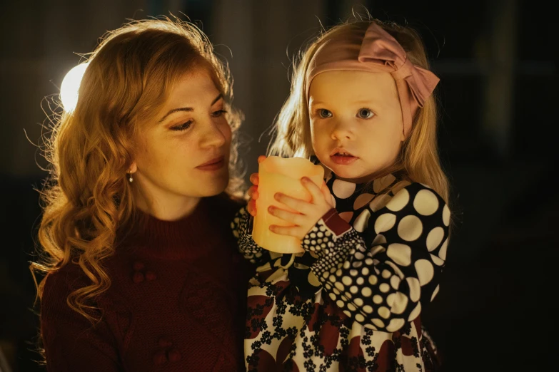 a mother and daughter drinking from a glass