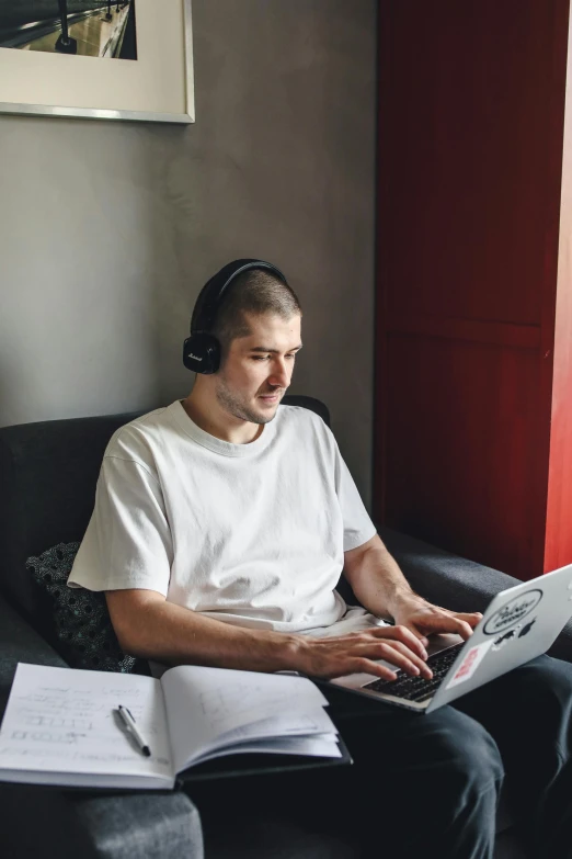 man wearing headphones and listening to music with his laptop