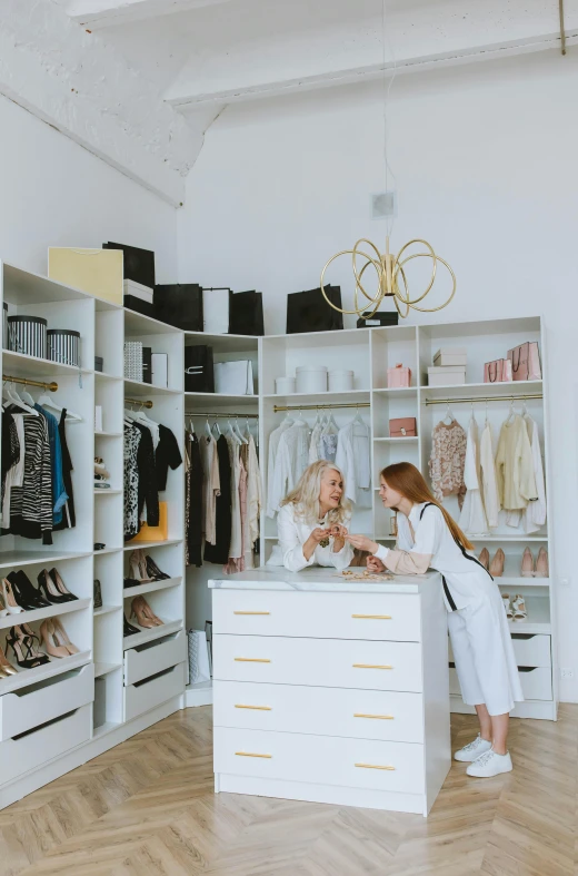 two women in the corner of a clothes store with shelves