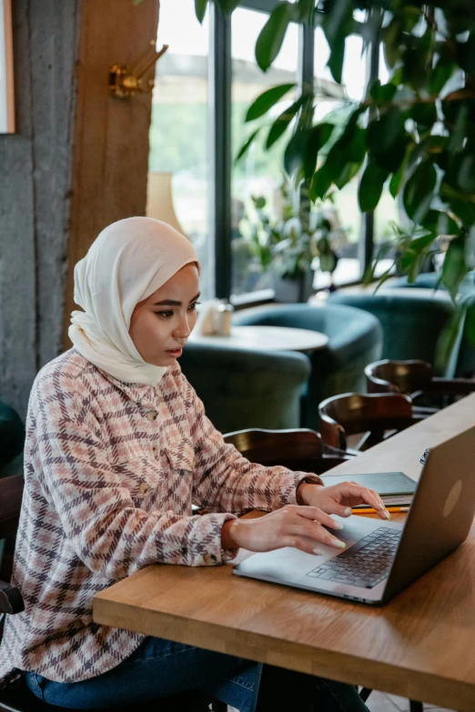 a young woman in hijab working on a laptop