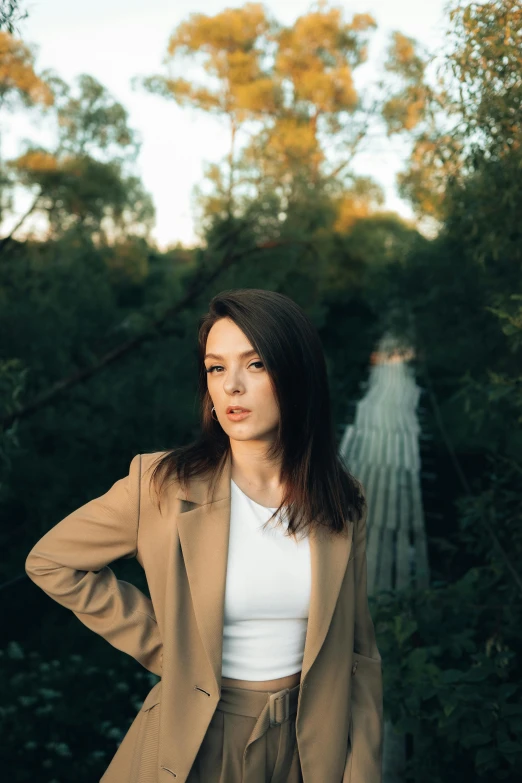 a woman standing in front of trees, with her arms behind her back