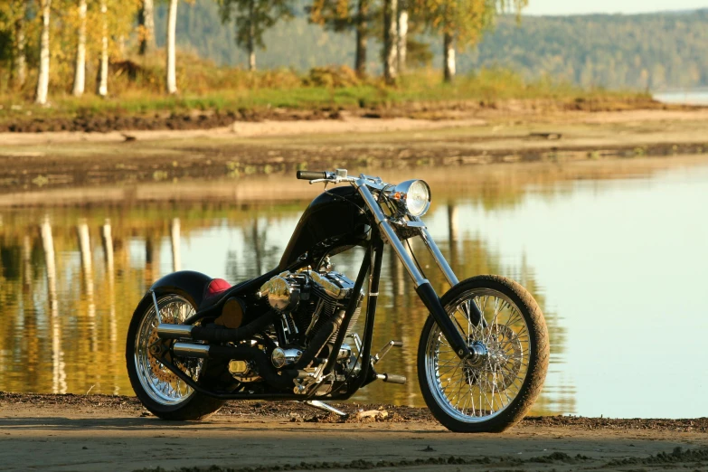 a motorcycle parked near water and forest in the background