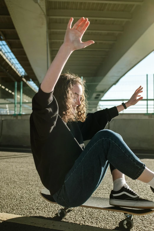 a skateboarder has her hands up and is sitting