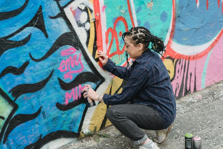 a woman painting a graffiti wall with a can