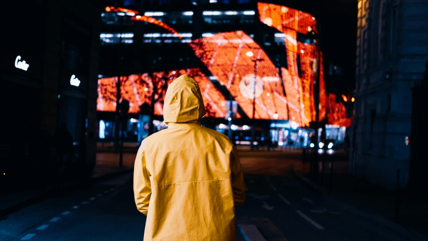 a person in yellow jacket walking down street with building in background