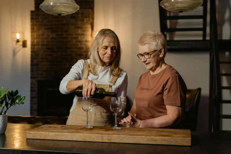 two women pouring wine at a table with a plant on it