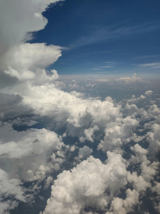 an airplane flies over a cloud filled blue sky