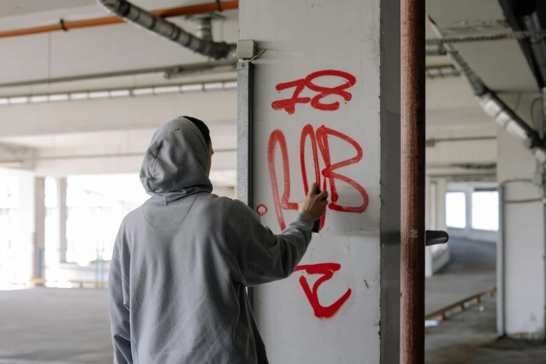 a man writes graffiti on a wall inside a building