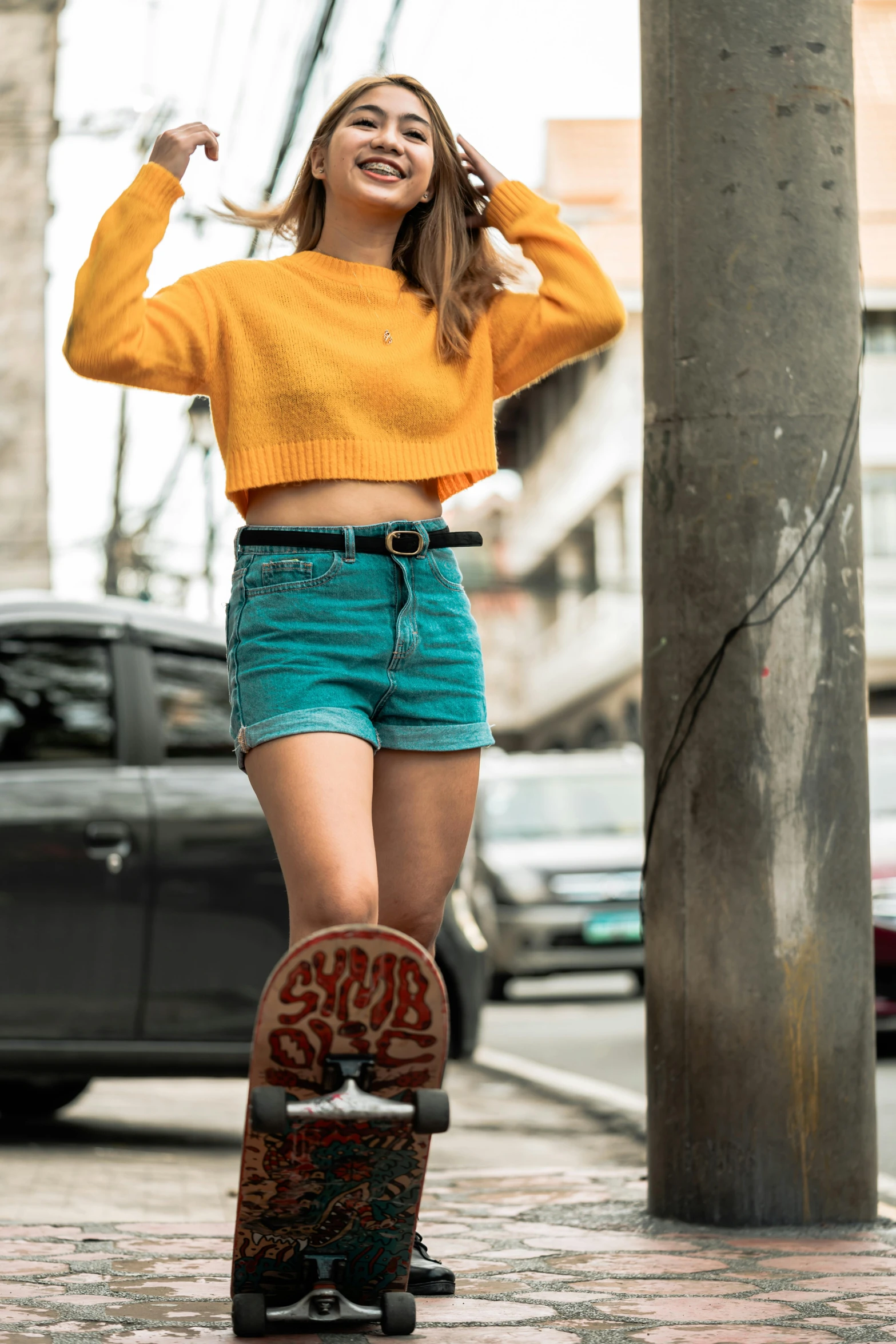 a beautiful young woman riding a skateboard down a street