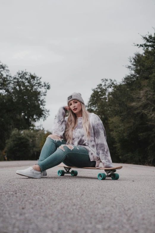 a young woman is sitting on her skateboard on the side of the road