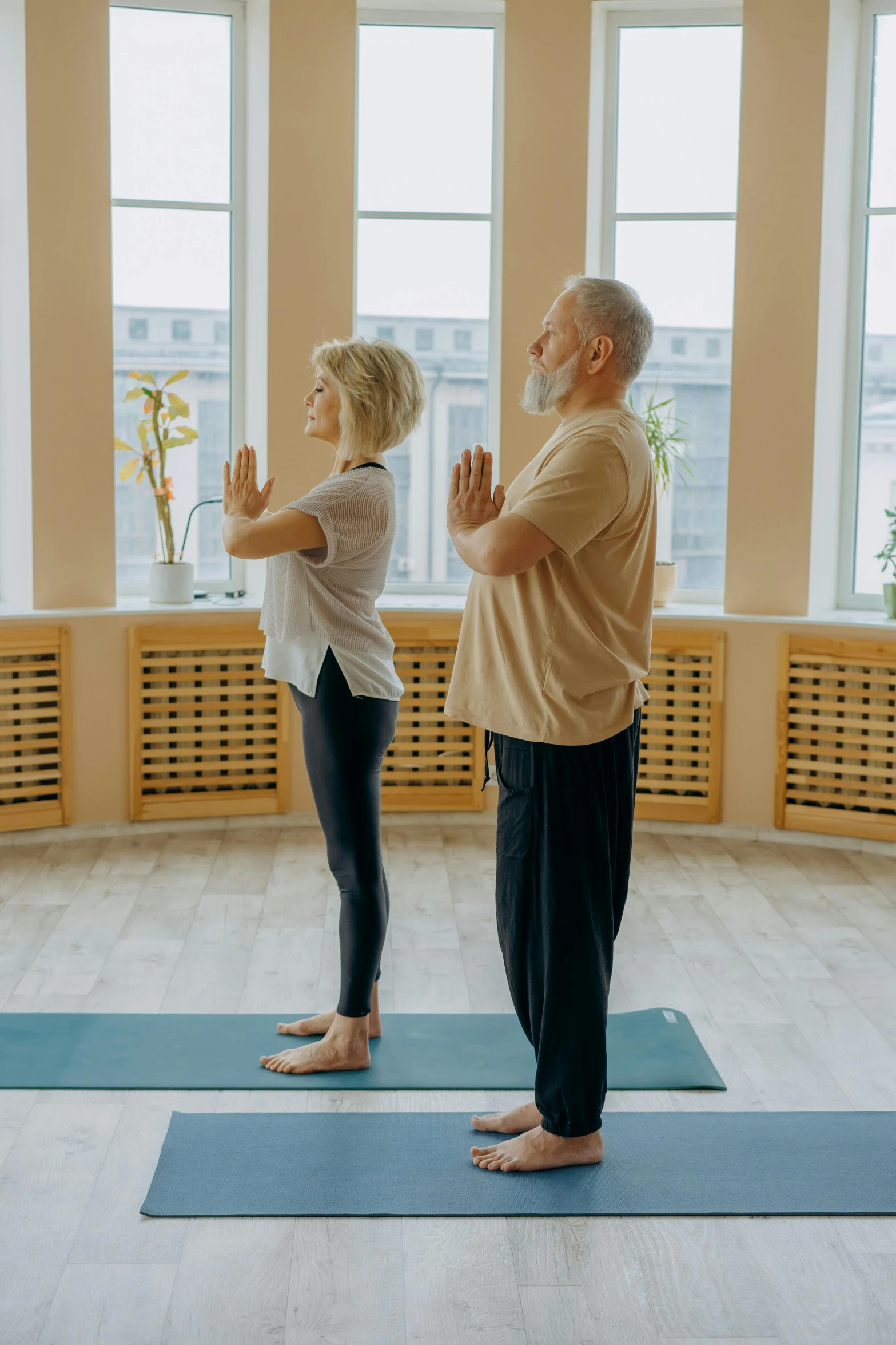 an older couple doing a yoga pose on a mat