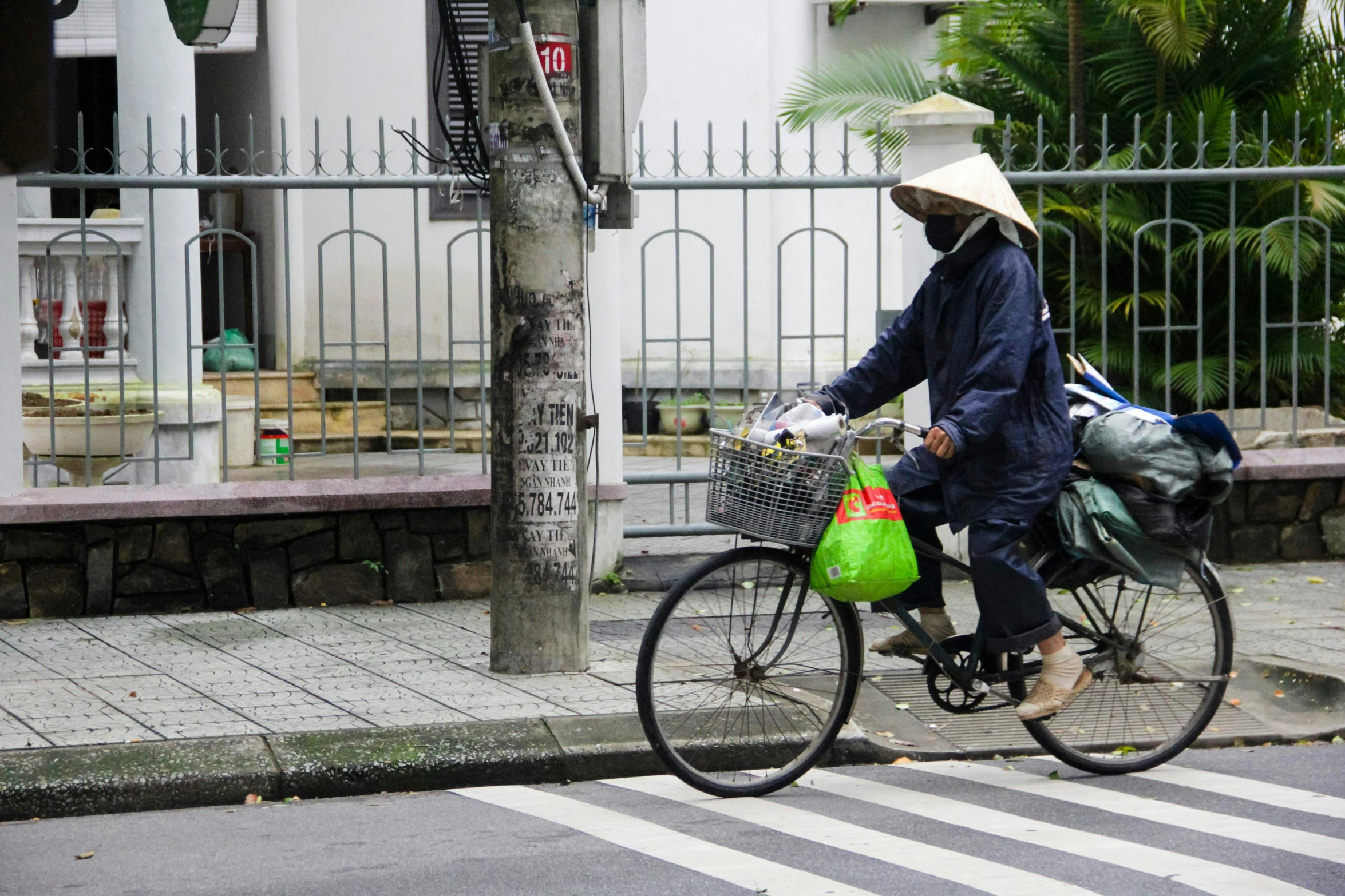 an asian man rides a bicycle with groceries in a basket