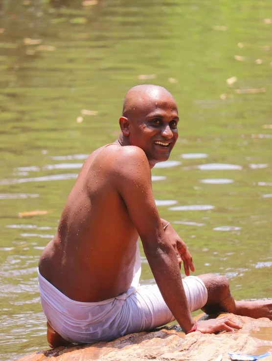 an older man sitting in the water near some rocks