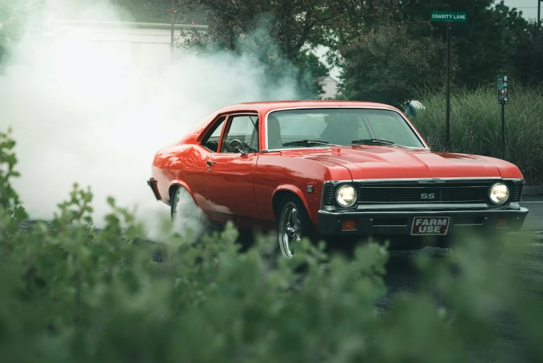 an old school red ford mustang smokes in the street