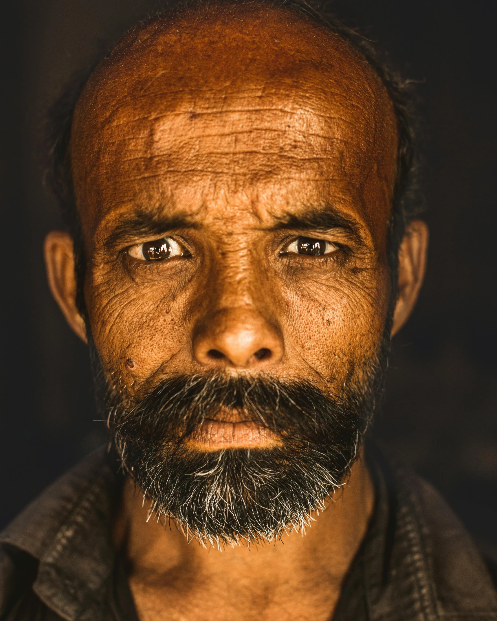 a man with a beard and blue eyes stares off into the distance